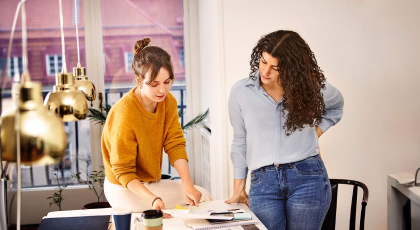 Two women looking at paperwork on a table in the office