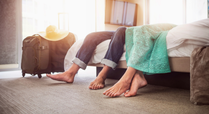 Two people sitting on a bed and their luggage on the floor - close up detail