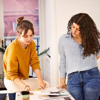 Two women looking at paperwork on a table in the office